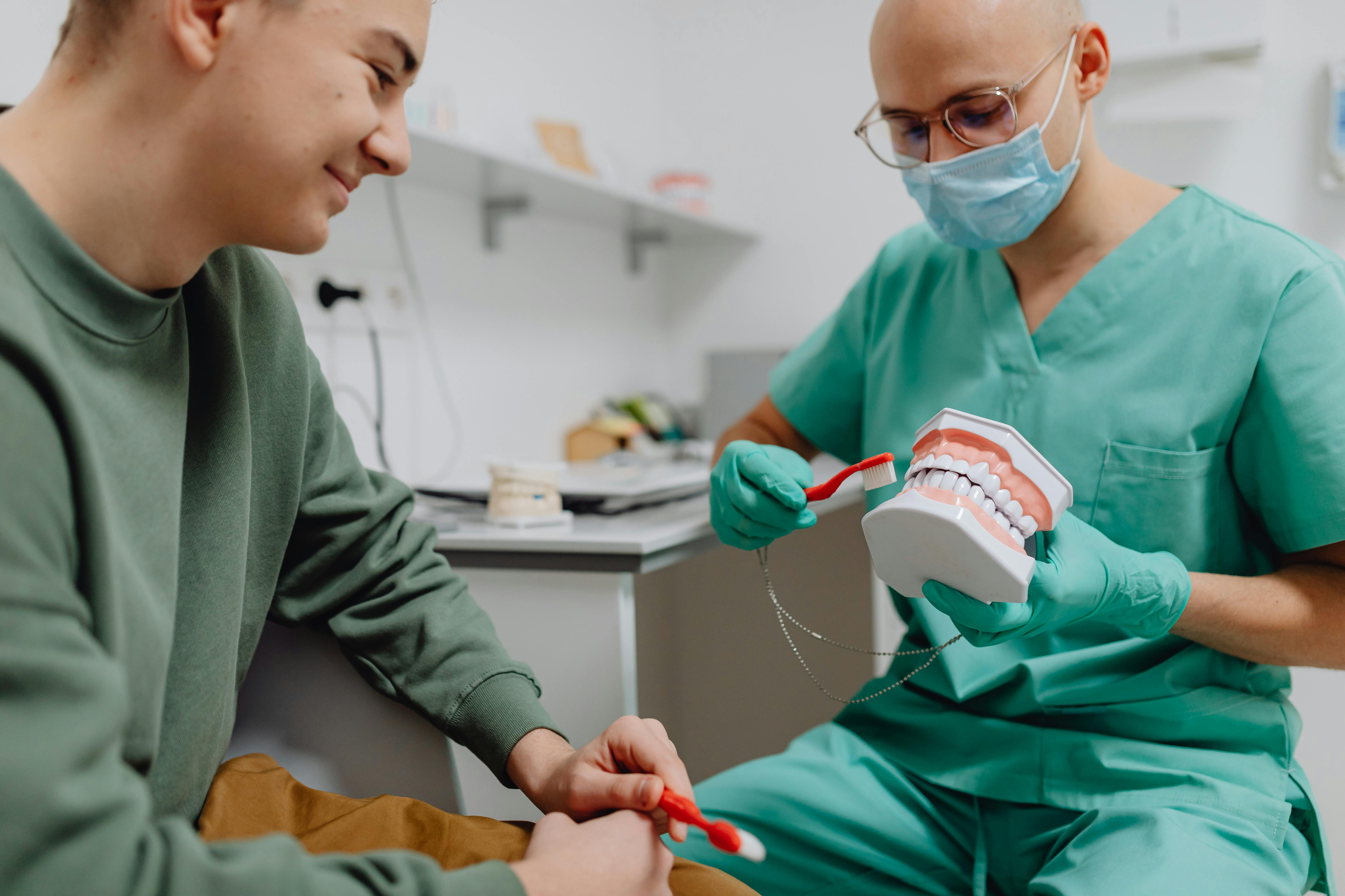 Dental hygienist showing patient how to brush teeth