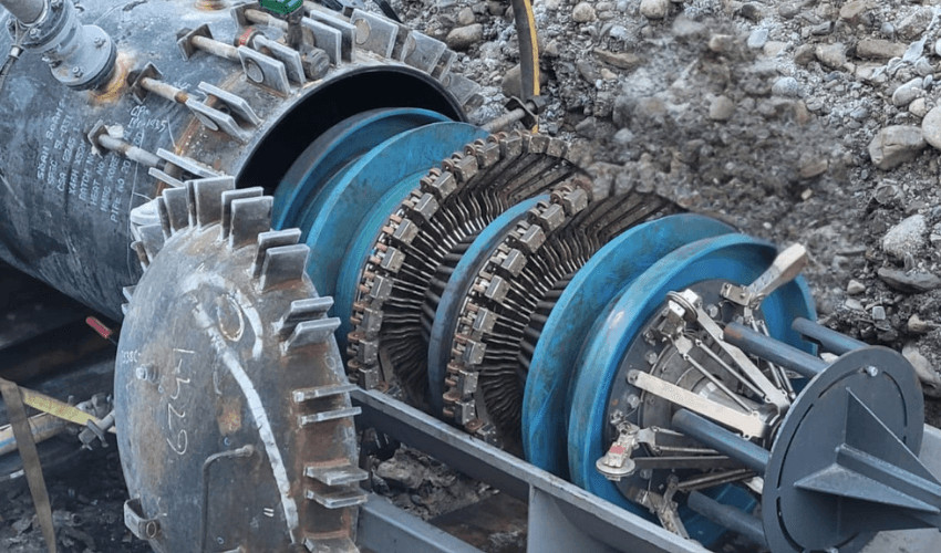 Close-up of a disassembled industrial machine with blue and metallic components, showing intricate mechanics and blades.
