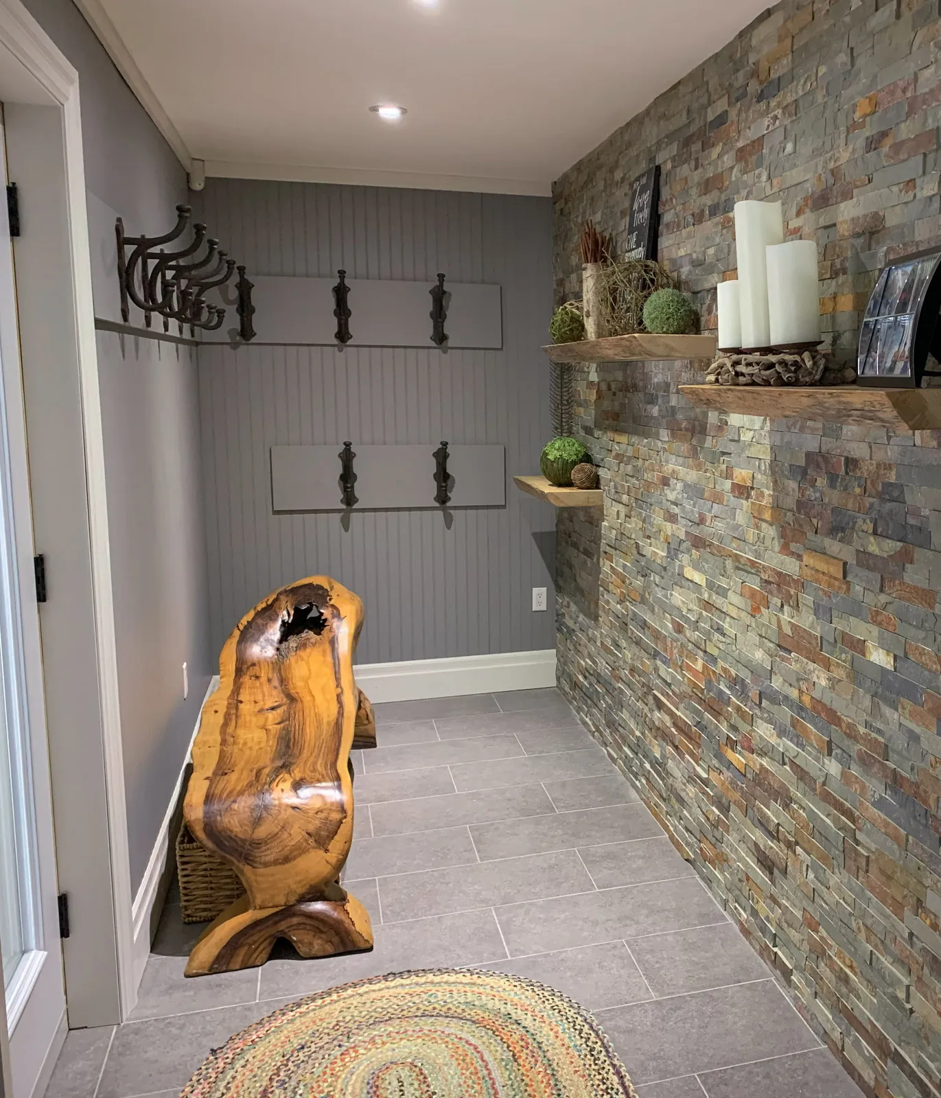 Mudroom entrance with custom granite masonry and hand-built live edge cedar bench.