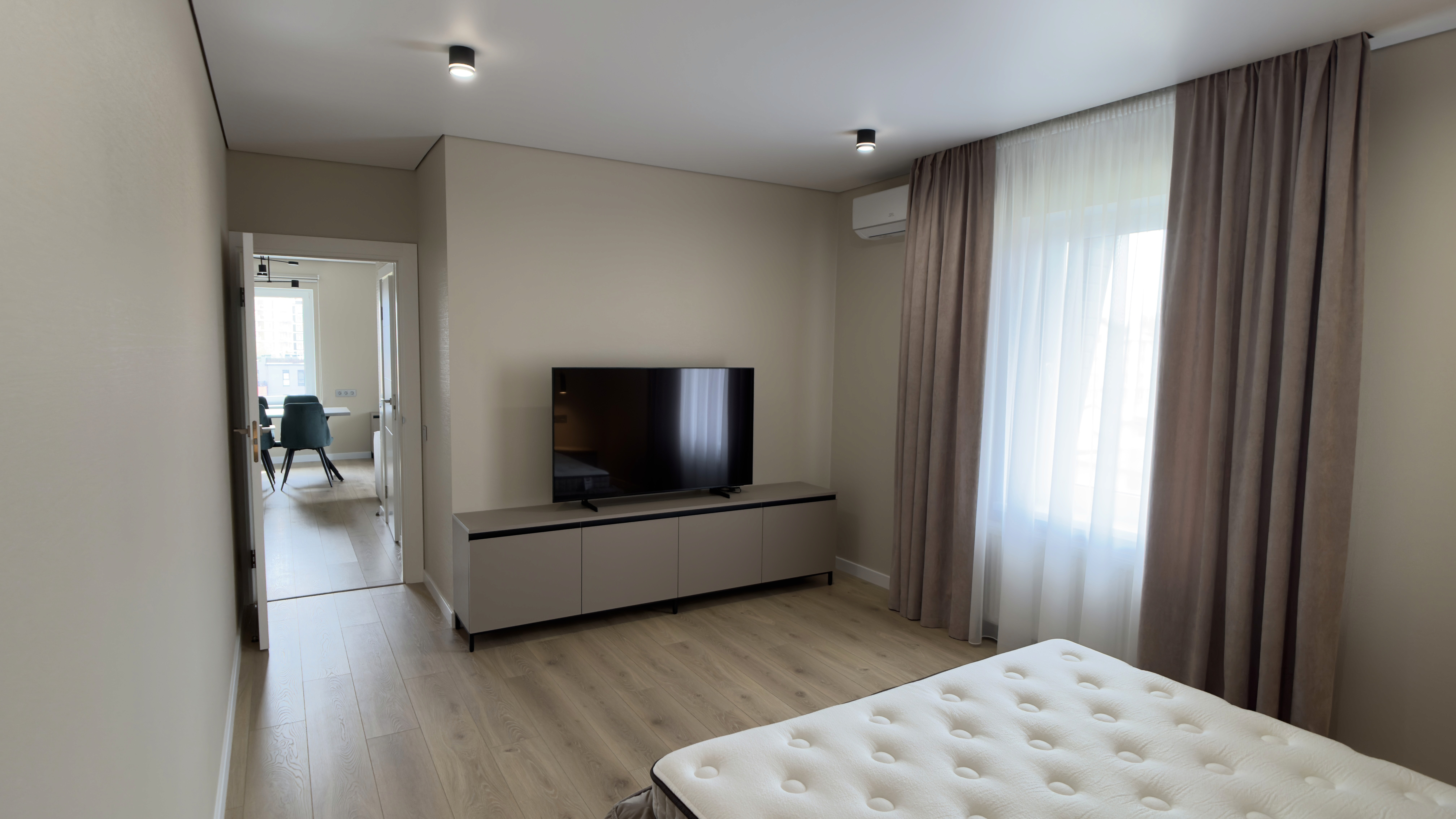 Вид зі спальні на телевізор, комод та двері до кухні-студії