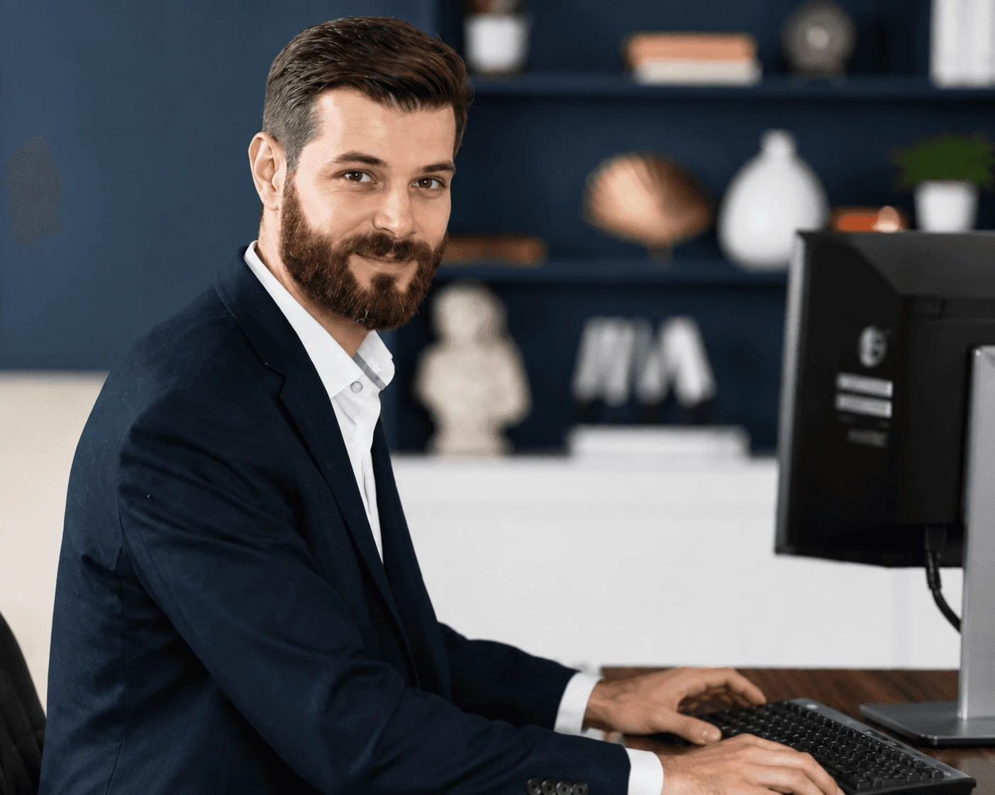 Business professional working at a desktop computer in a modern office.