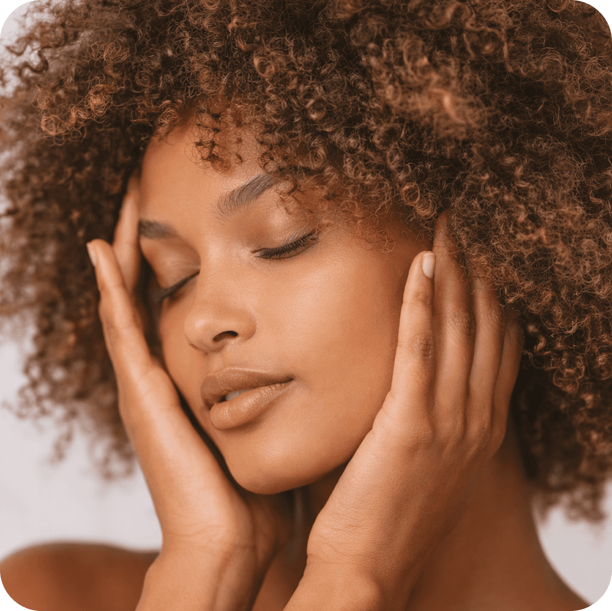 Smiling woman holding a rose quartz face roller, using it for a self-massage on her face
