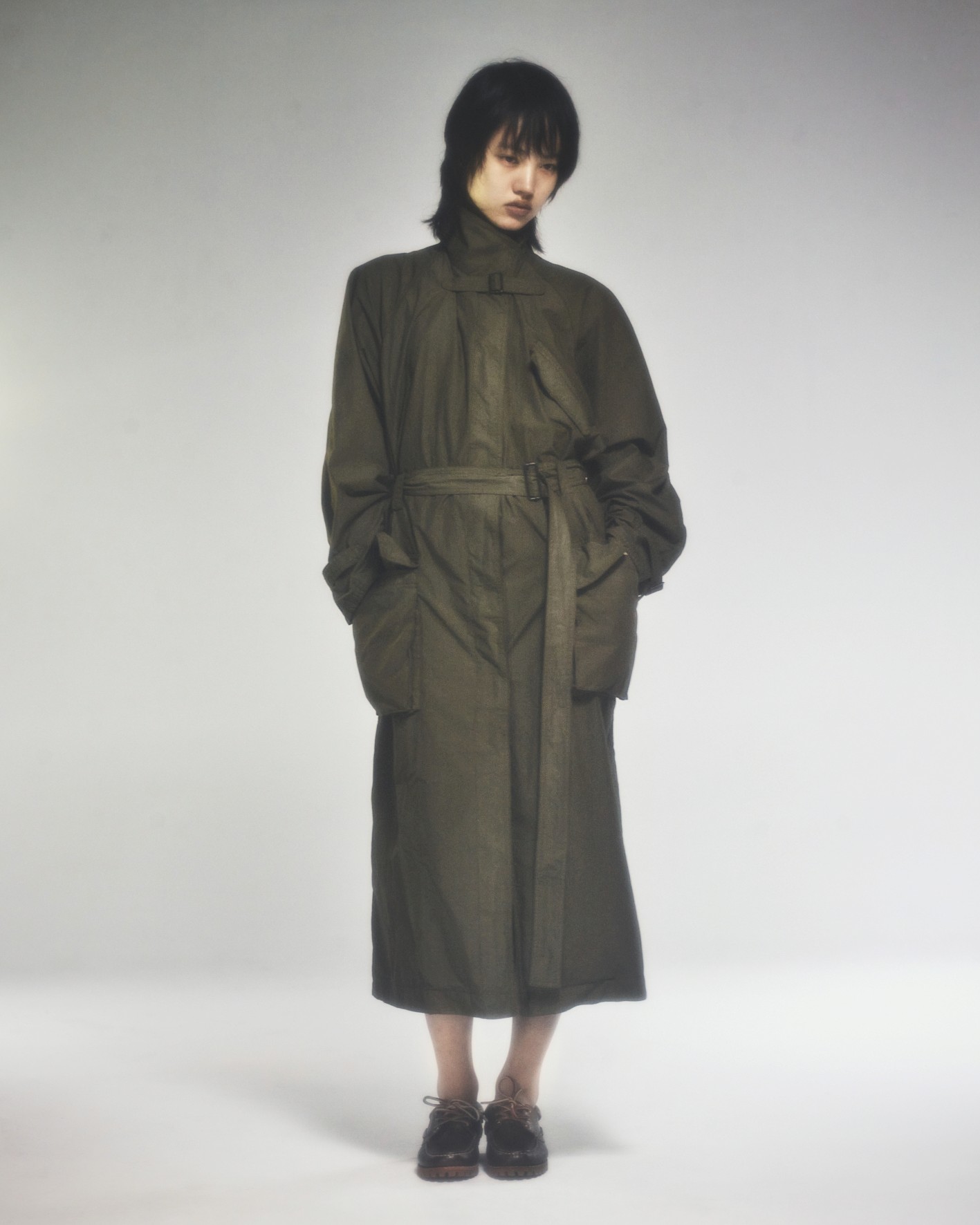 Sur un fond neutre,une mannequin porte un trench vert militaire