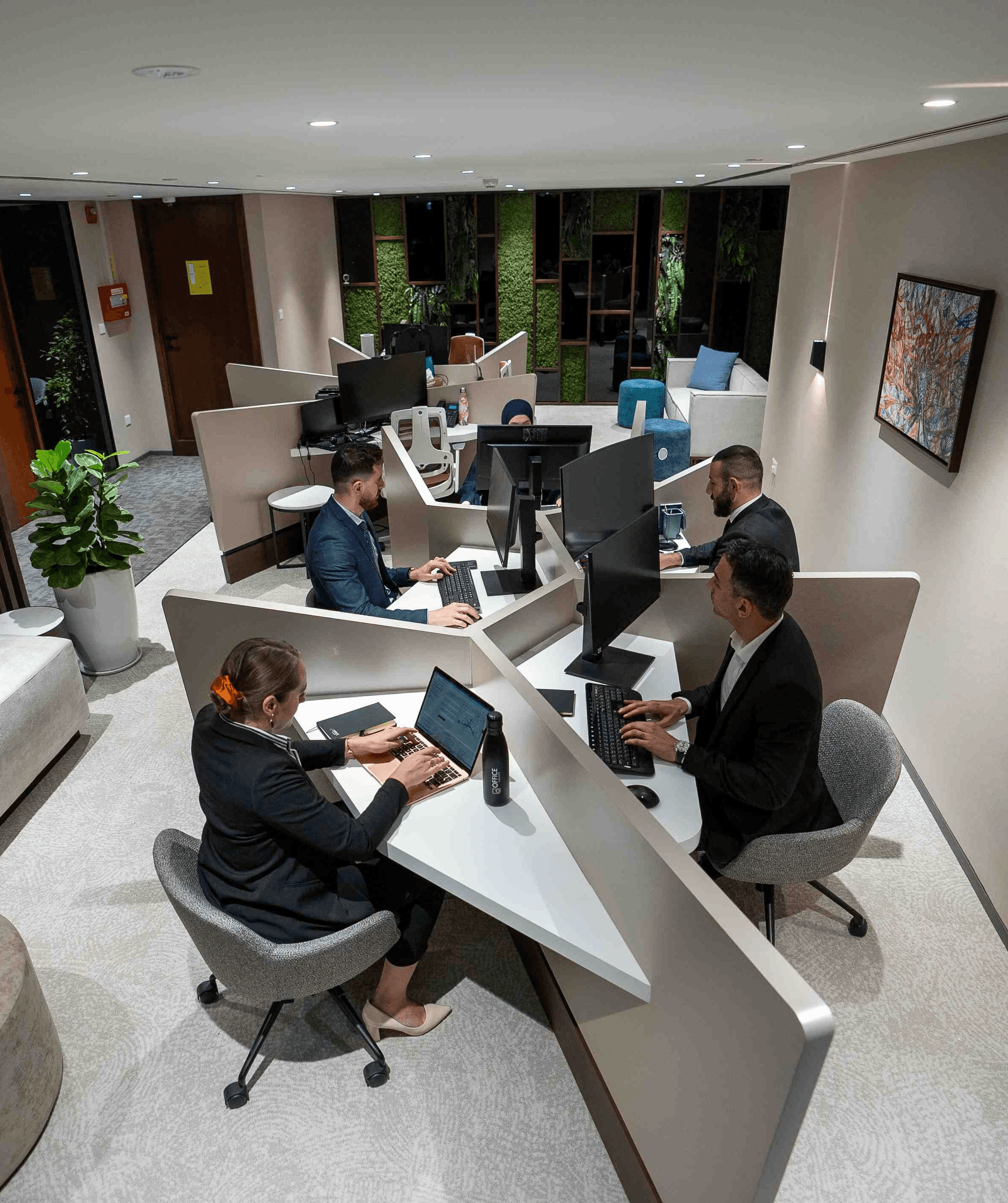 Lounge area with soft seating and greenery walls in a coworking space in Abu Dhabi.