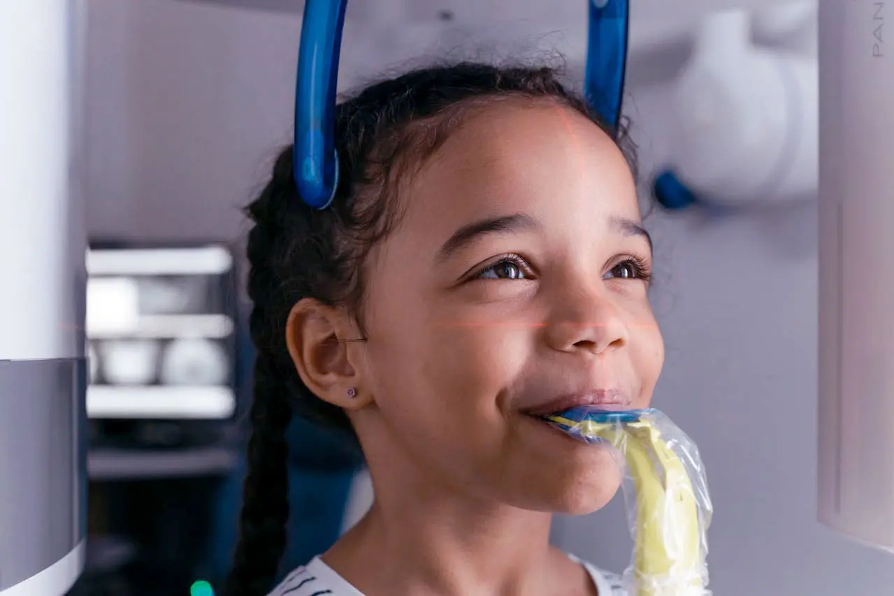 Child smile while holding dental device in their mouth. 