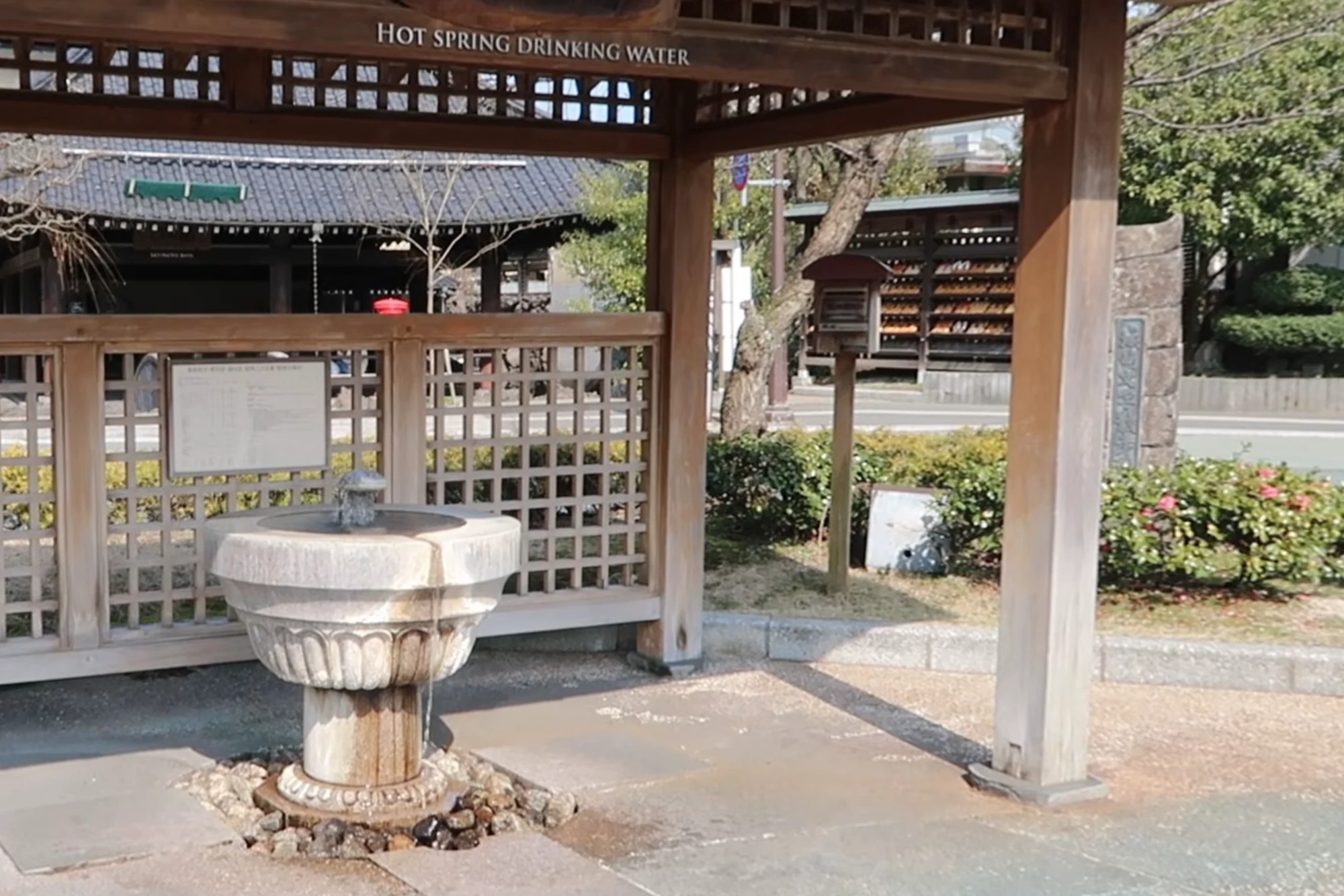Timber pavilion over two stone drinking basins signed Hot Spring Drinking Water in Kinosaki.