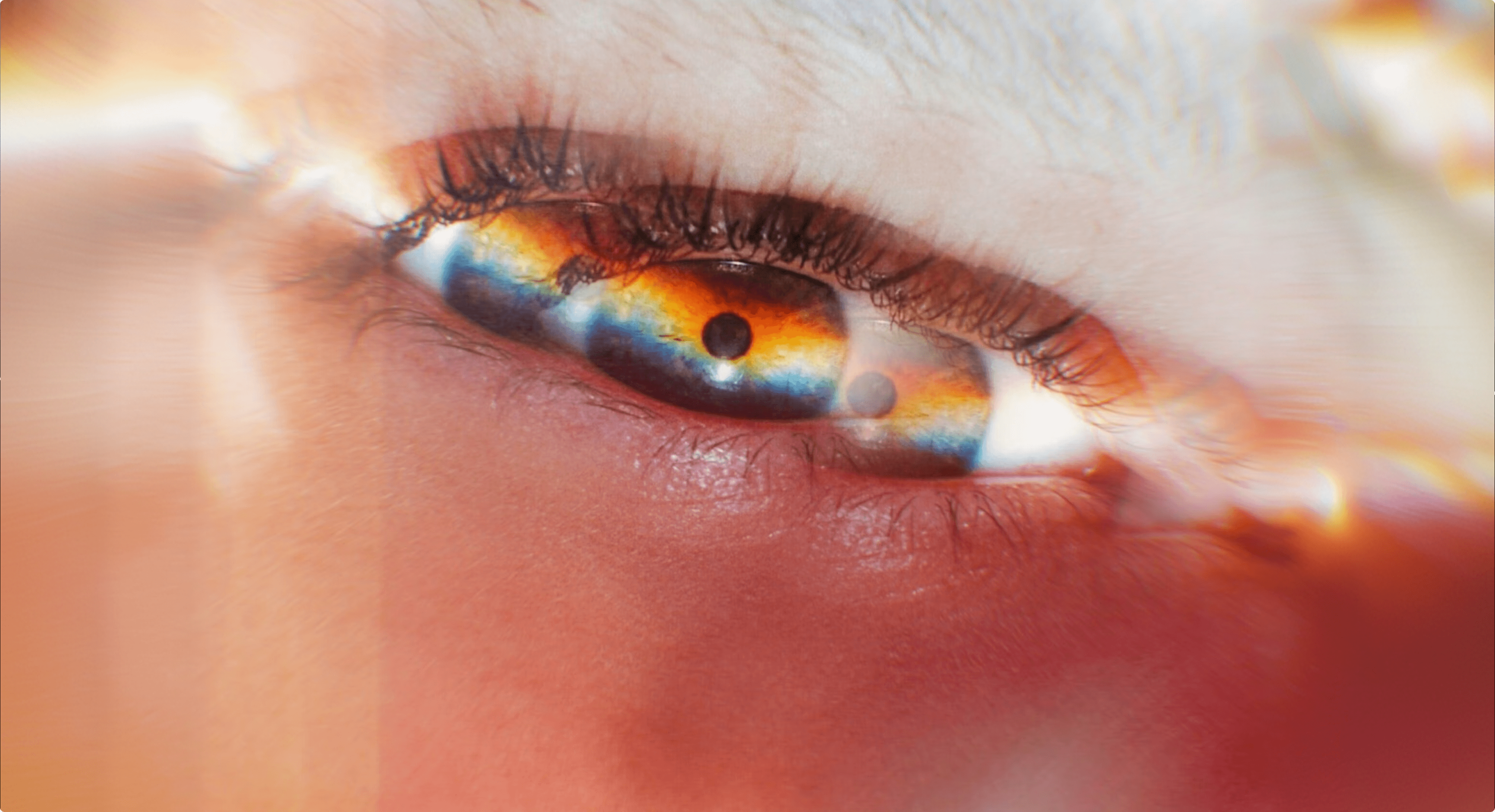  An extreme close-up of a human eye with a dreamlike, prismatic light effect creating rainbow colors across the iris and lens flare around the edges