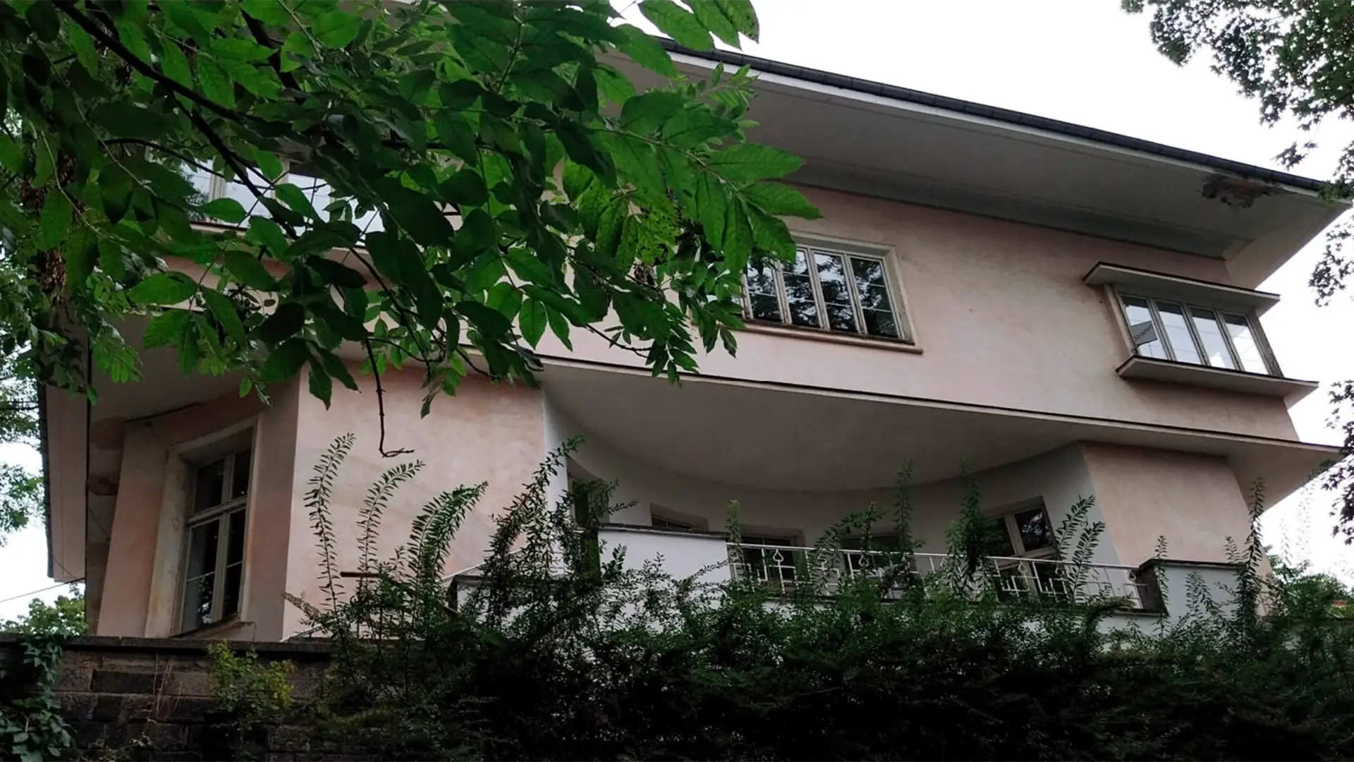 Fasáda vily s původními okny a zelení. Dům, který se navzdory zpoždění chystá na oslavu stého výročí.