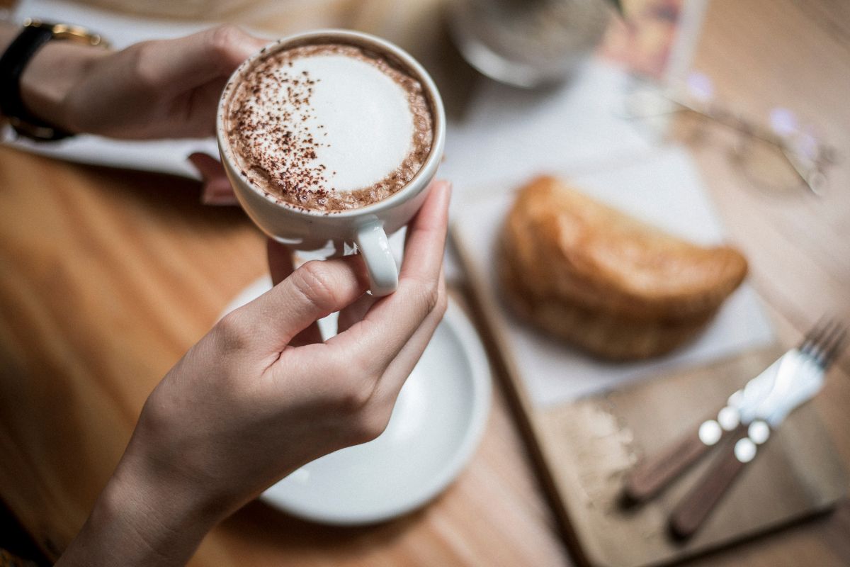 Holding a cup of coffee with bread on the side