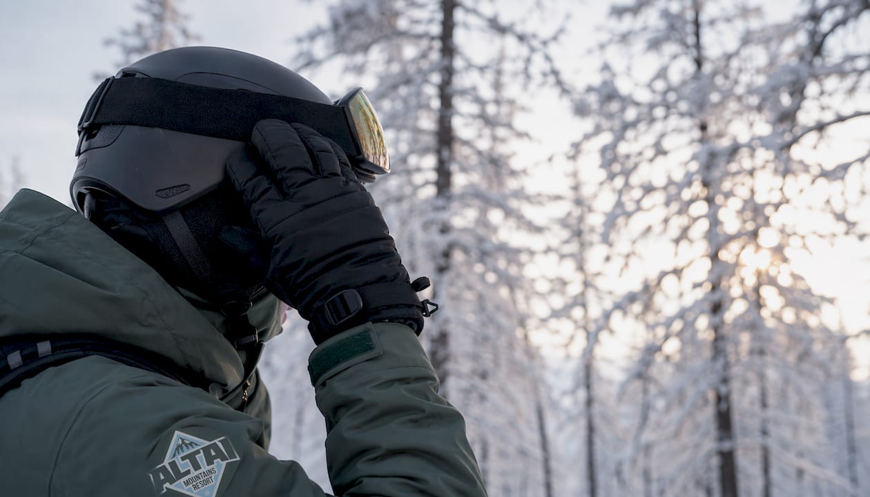 Hands adjusting a winter sports helmet and goggles