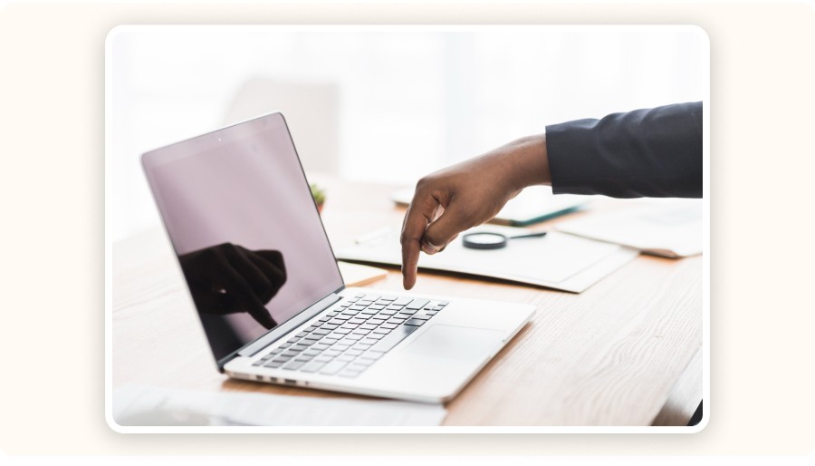 Hand pointing at laptop keyboard on desk with workspace setup