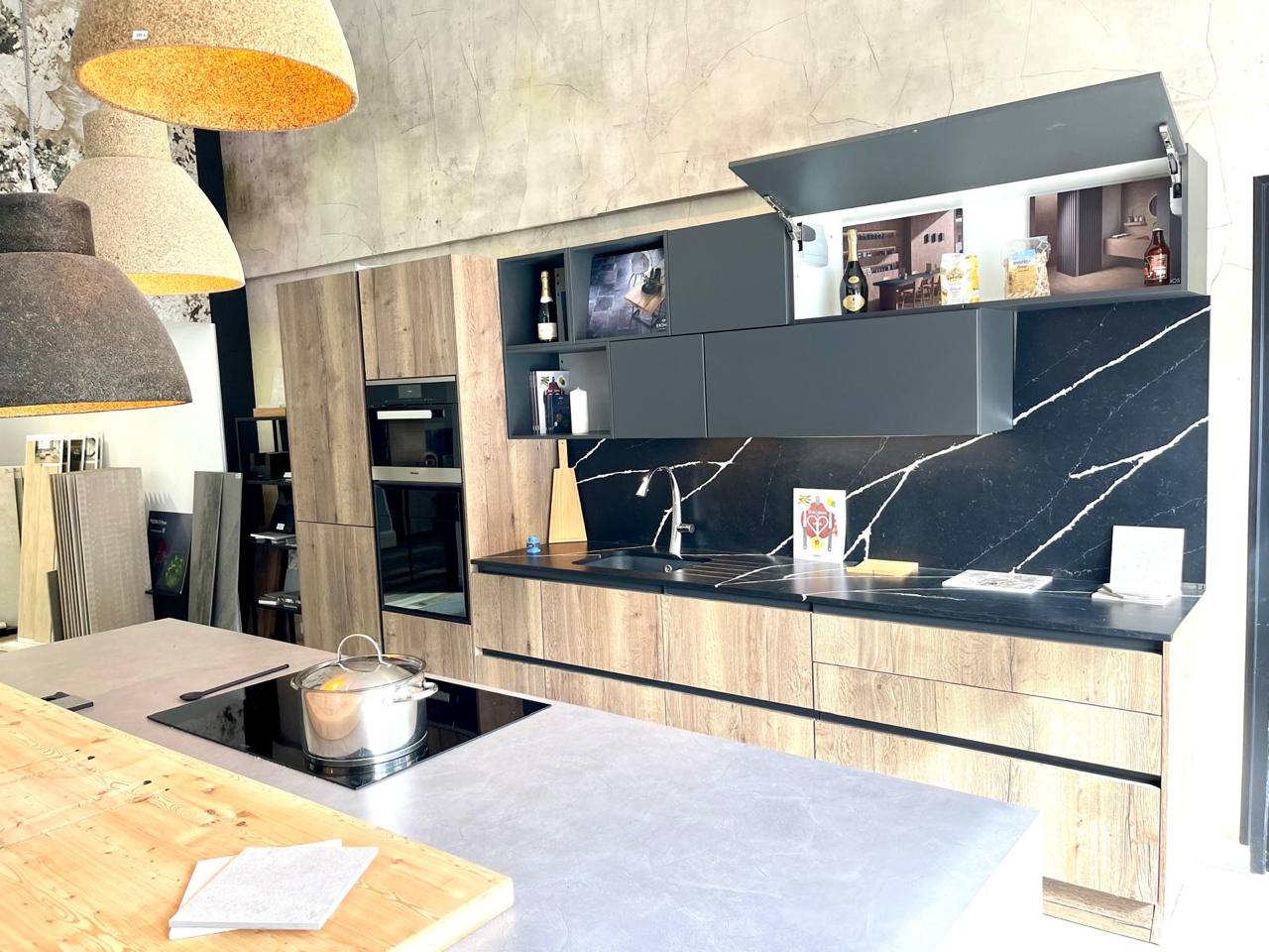 Cuisine showroom 77 avec armoires bois noir, dosseret marbre et fours encastrés, exposition cuisines modernes.