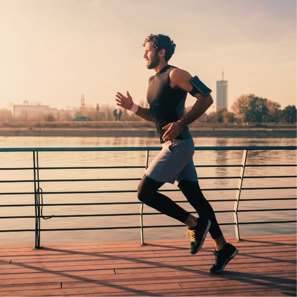 Woman sitting holding a green apple in gray workout wear smilling