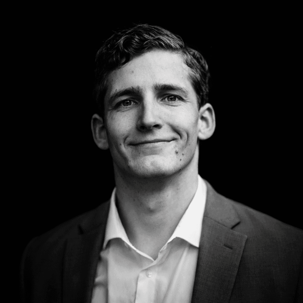 Portrait of a woman with straight long hair, in a dark t-shirt, set against a neutral backdrop.