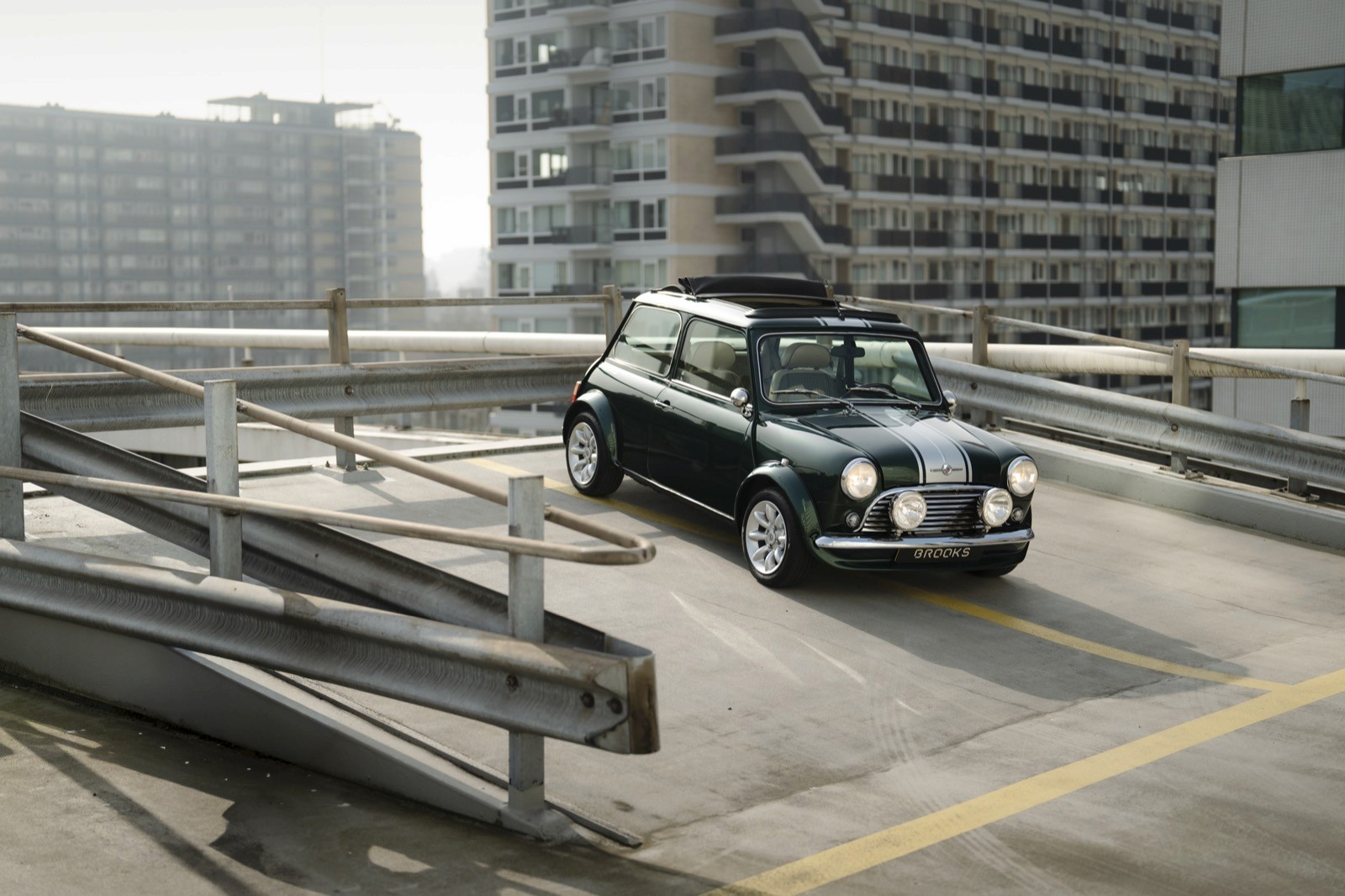 A small vehicle parked on a rooftop garage surrounded by tall buildings in an urban setting.
