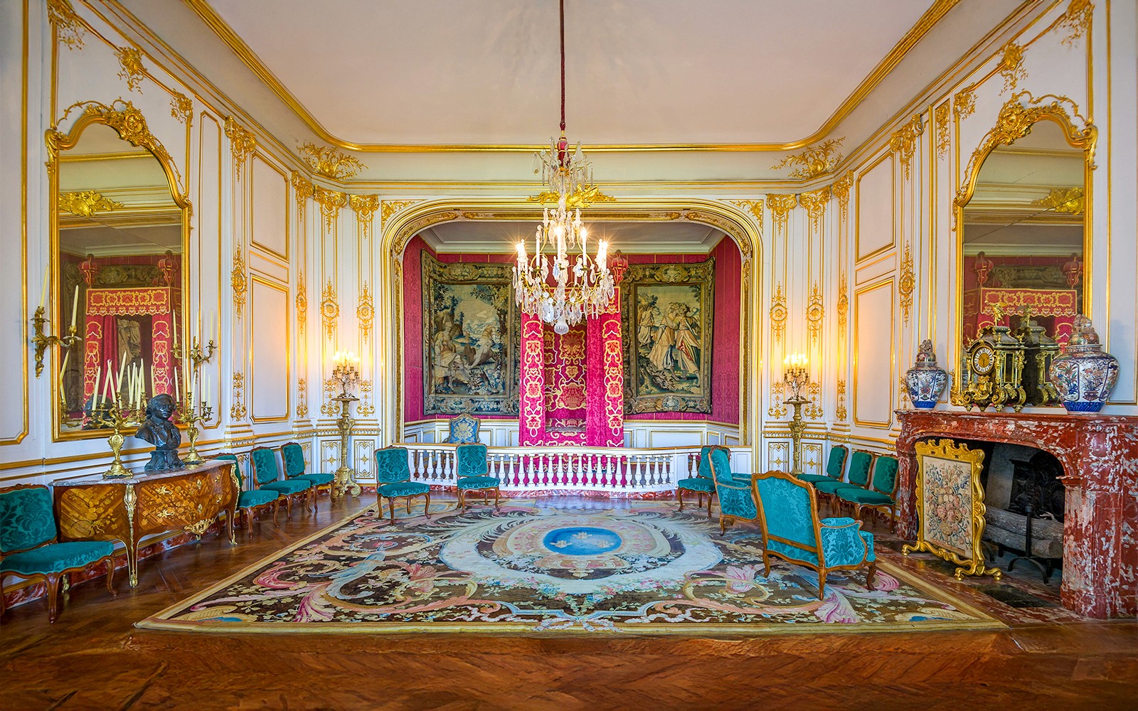 Chambord Castle king's room with ornate decor, tapestries, and chandelier.