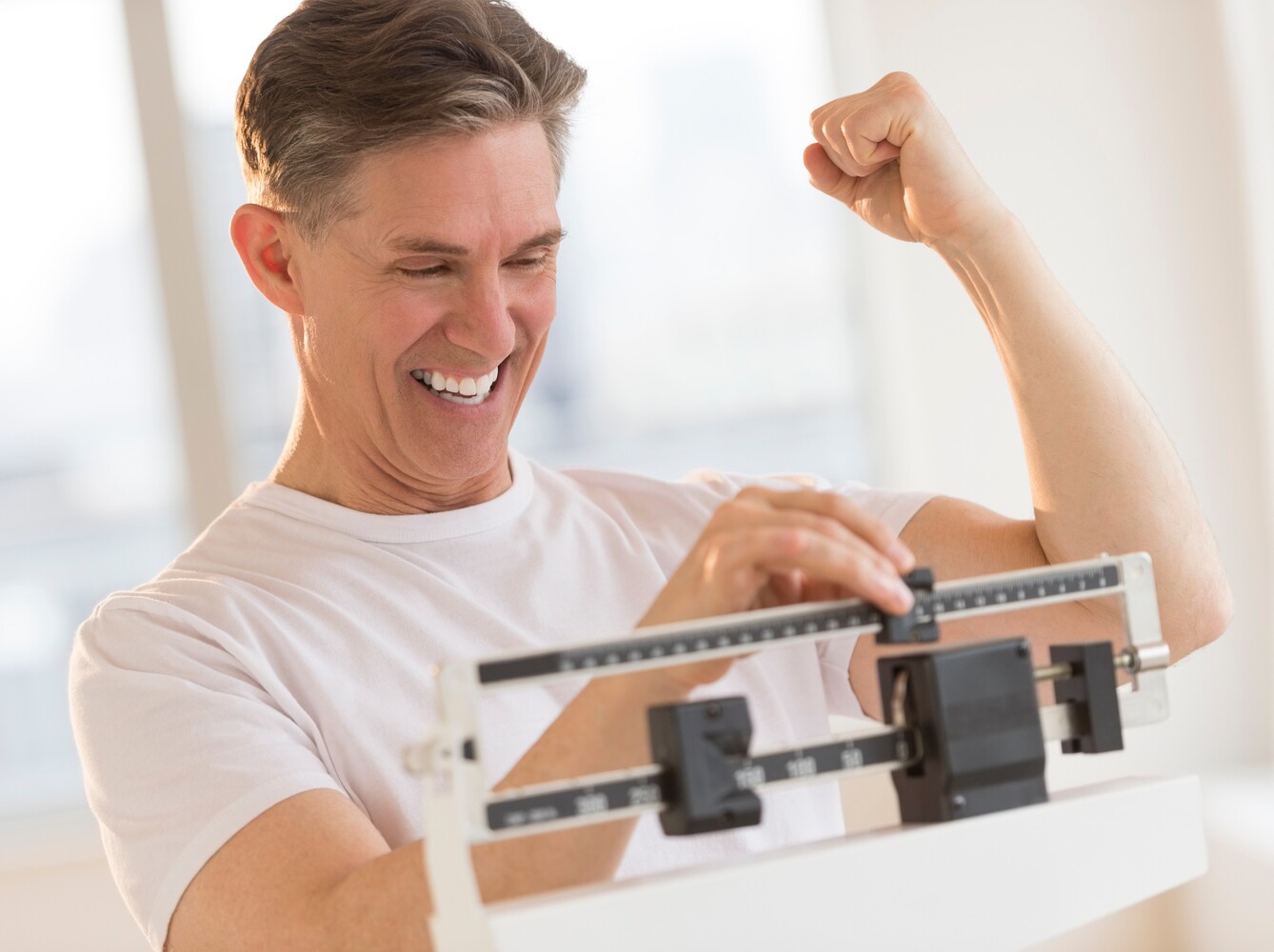 man excitedly checking the results of his stationary bike workout weight loss routine on a scale