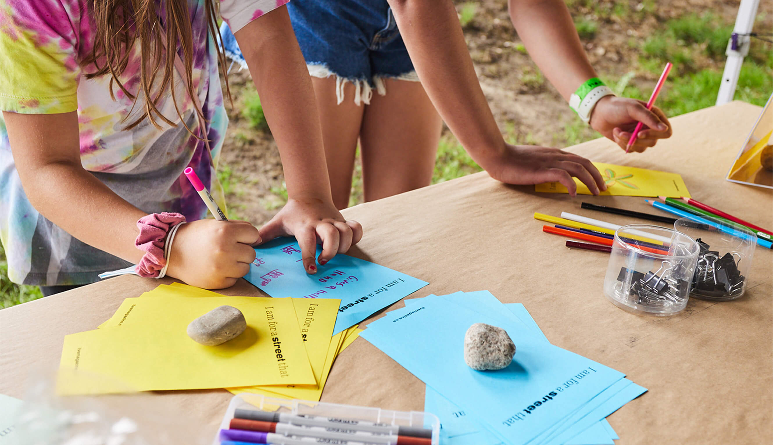 Two young participants writing and sketching on event materials.