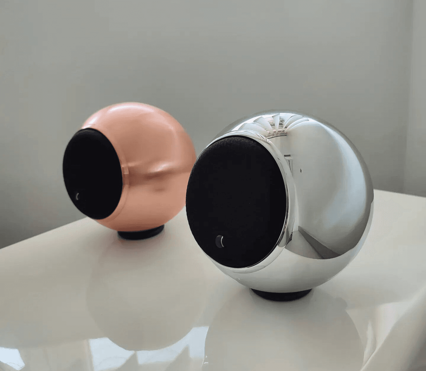 Two spherical speakers, one copper, one chrome