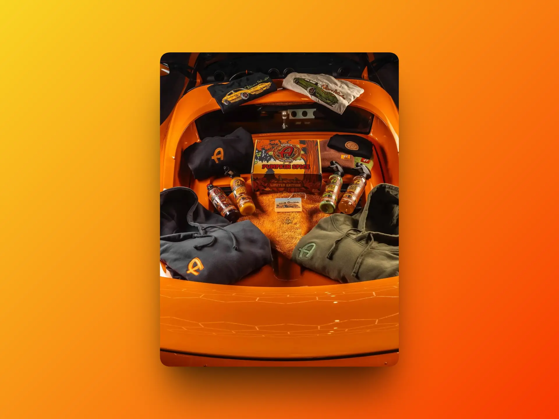 Adams Polishes Pumpkin Spice Car Care Collection 2025 displayed in the boot of an orange car, featuring limited edition box set, detailing products, hoodies, T-shirts, and seasonal merchandise.