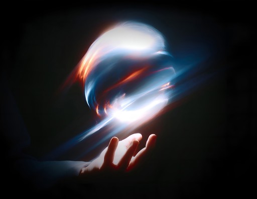 Abstract glowing orb of blue and orange light floating above an outstretched hand against a dark background.