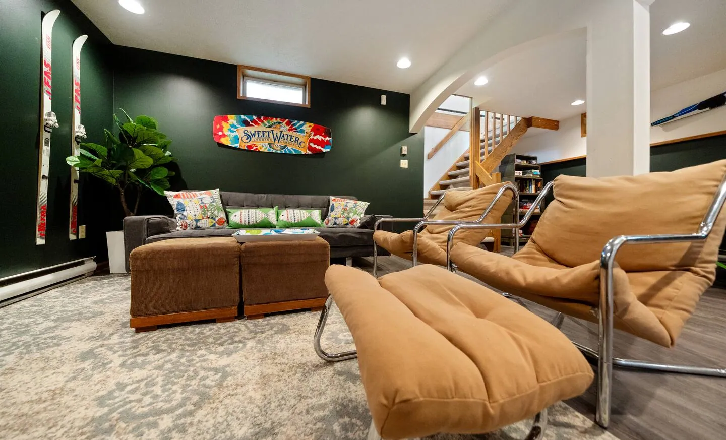 Lower family room with leather lounge chairs, ottomans and dark green walls at Lake Front, Lake Naomi