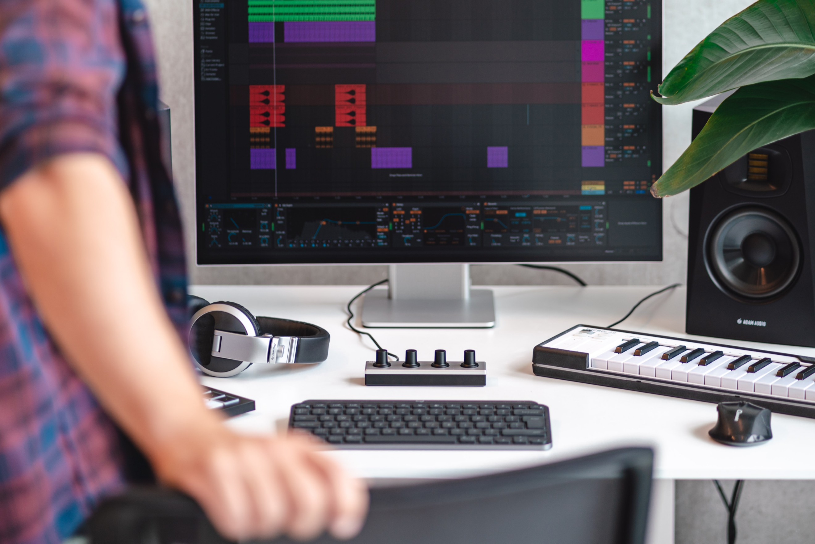 An angled lifestyle shot of the El4B MIDI controller by Engineeringlab, placed on a modern desk setup. The controller is surrounded by various music production tools, like a laptop, headphones, and speakers. Soft ambient lighting adds to the cozy, creative atmosphere, highlighting the sleek, minimalist design of the controller, with its clean buttons and knobs. The environment reflects an artistic workspace, suggesting a professional but relaxed vibe, perfect for music producers.