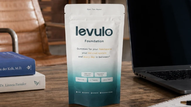 Levulo Foundation pouch on desk next to a macbook pro and the books " heal your nervous system" and "mind your body"