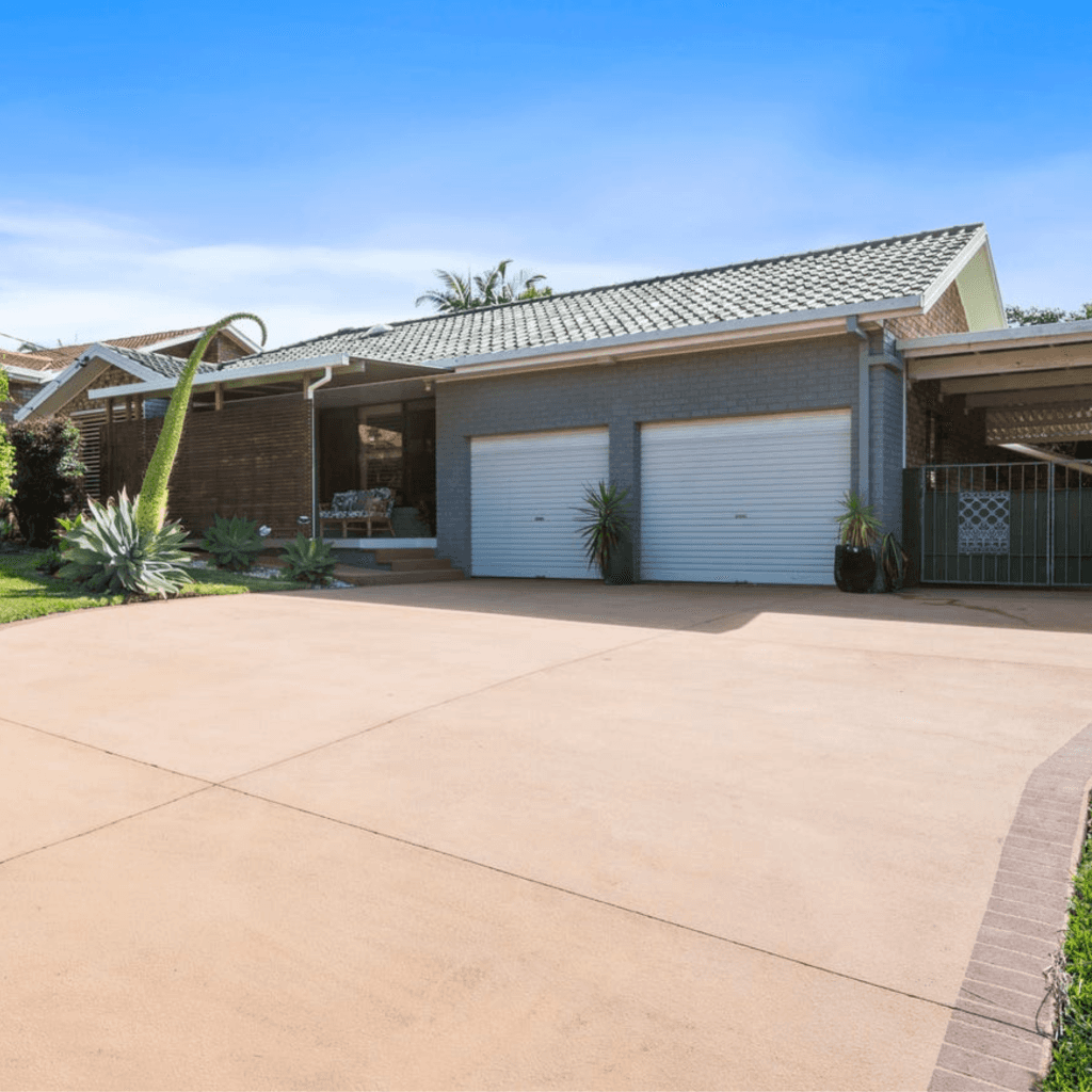 Grey brick house with two garage doors and driveway.