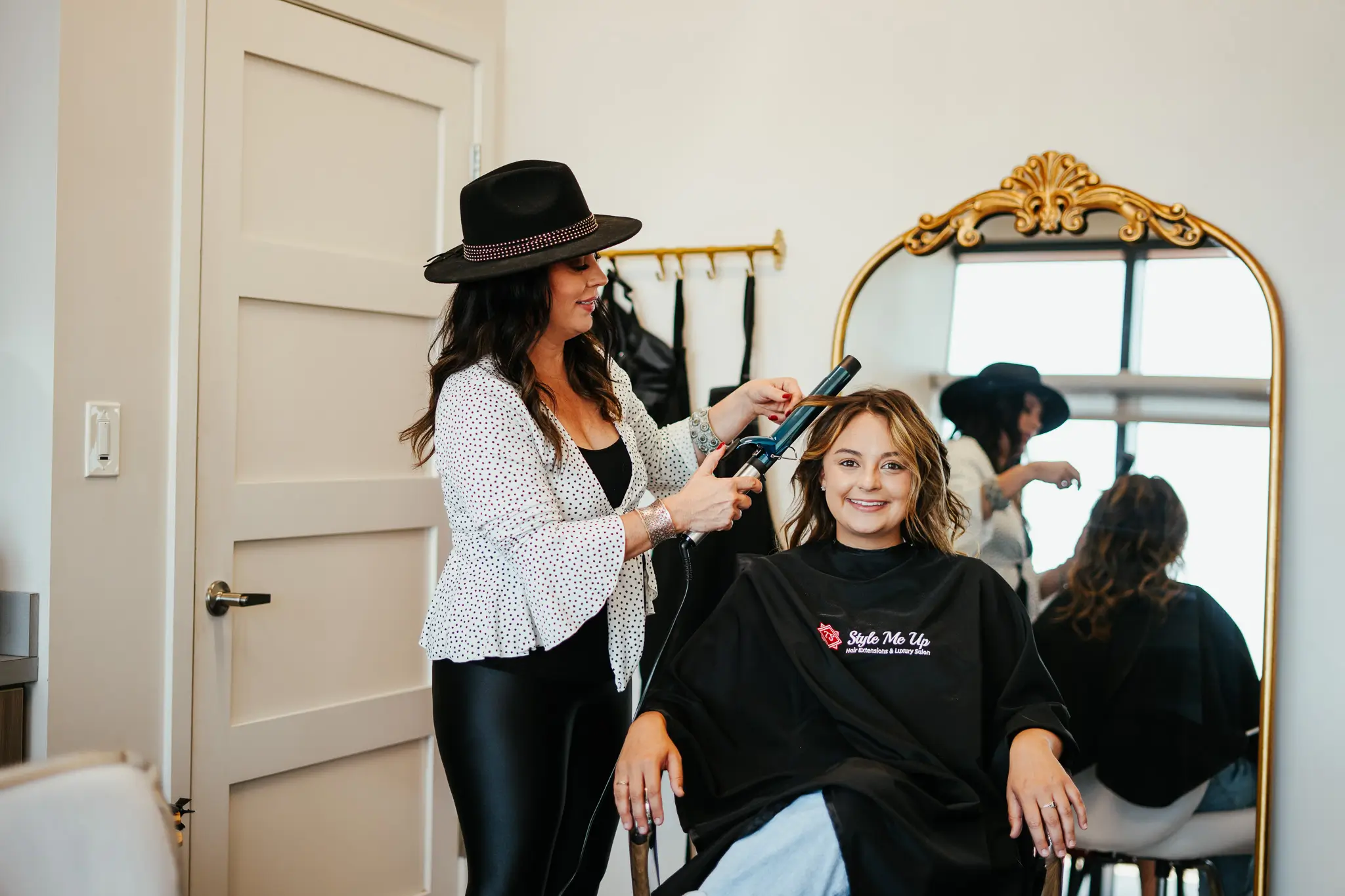 Photo of Tasha Smith, owner of Style Me Up, curling a young woman's hair.