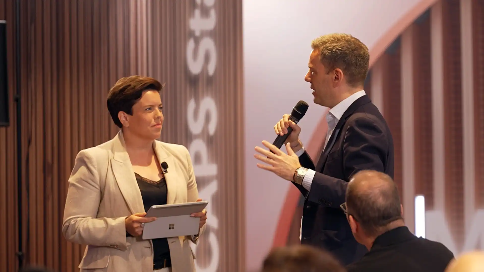 Live on-stage discussion between two speakers during a professionally produced corporate event.