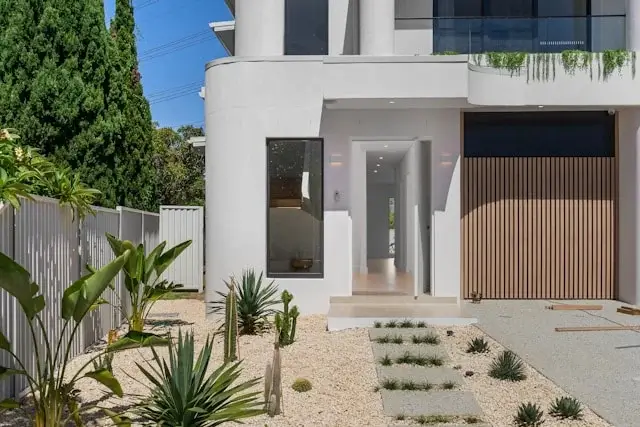 Modern white house entrance with minimalist landscaping, clean lines, and contemporary design.
