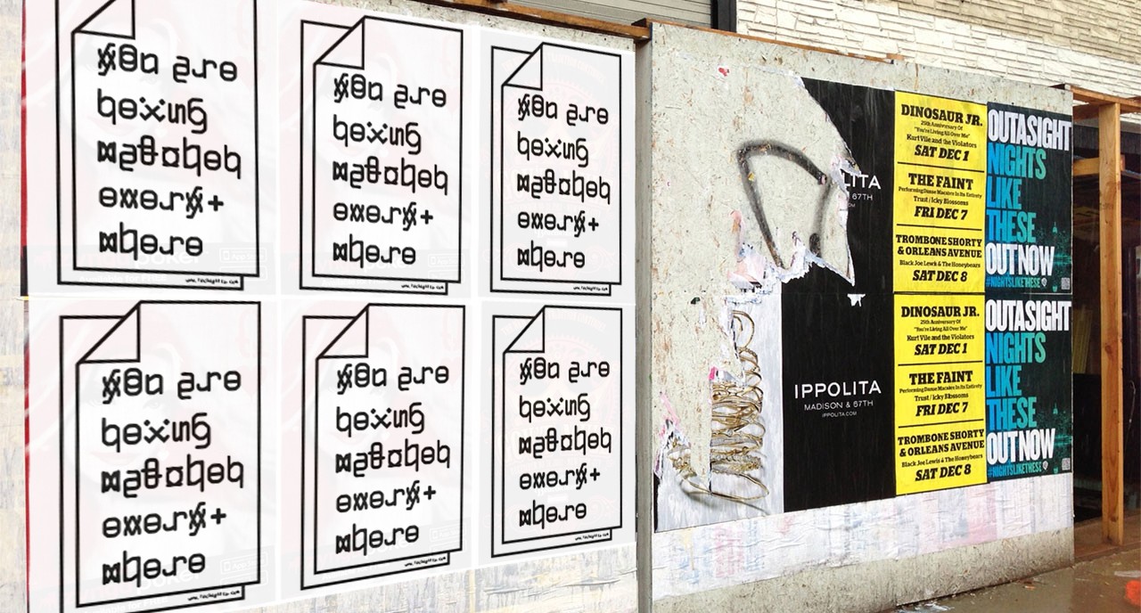 A photo showing some white posters with a paper page drawing on it and some text. There are also black, yellow and blue posters, some of them teared.
