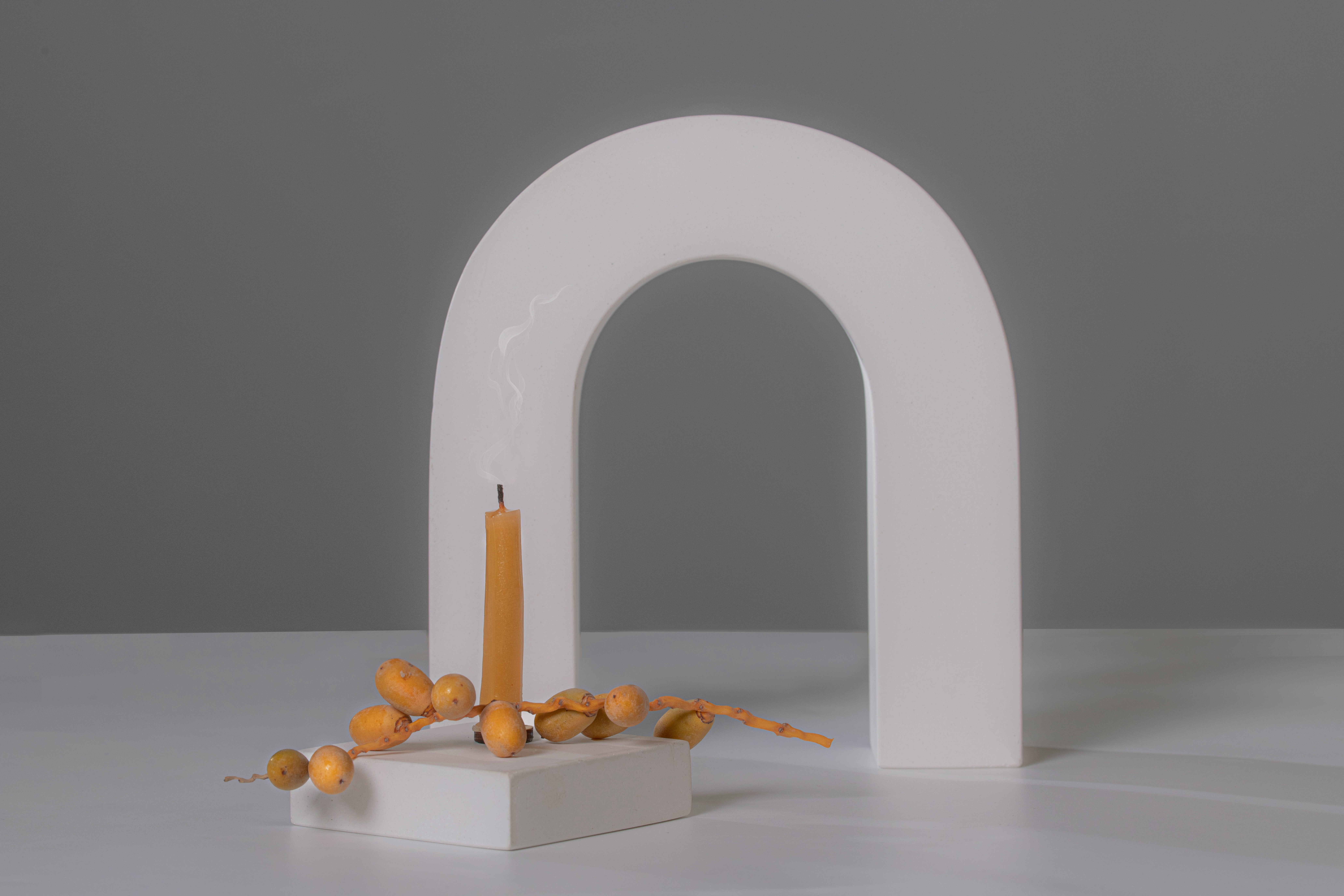 a white sculpture with a lit candle on top of it