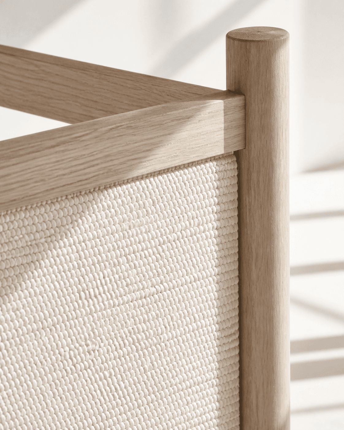 Detailed pale-oak joint beside a hand-woven ivory panel in soft daylight