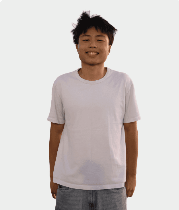 A smiling man with glasses and gray hair sits in a bustling cafe, surrounded by people and workspaces.