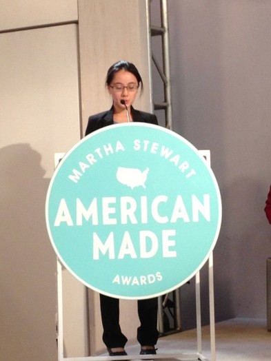 a woman giving a speech on the stand with the Martha Stewart American Made awards logo