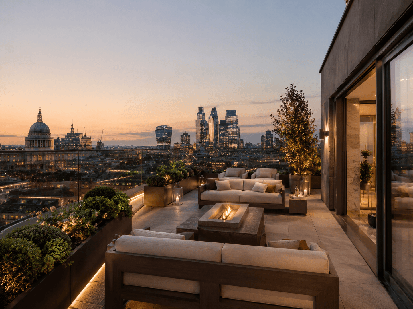 Private London penthouse rooftop terrace with outdoor lounge seating, fire pit, glass railings, greenery, and city skyline views.