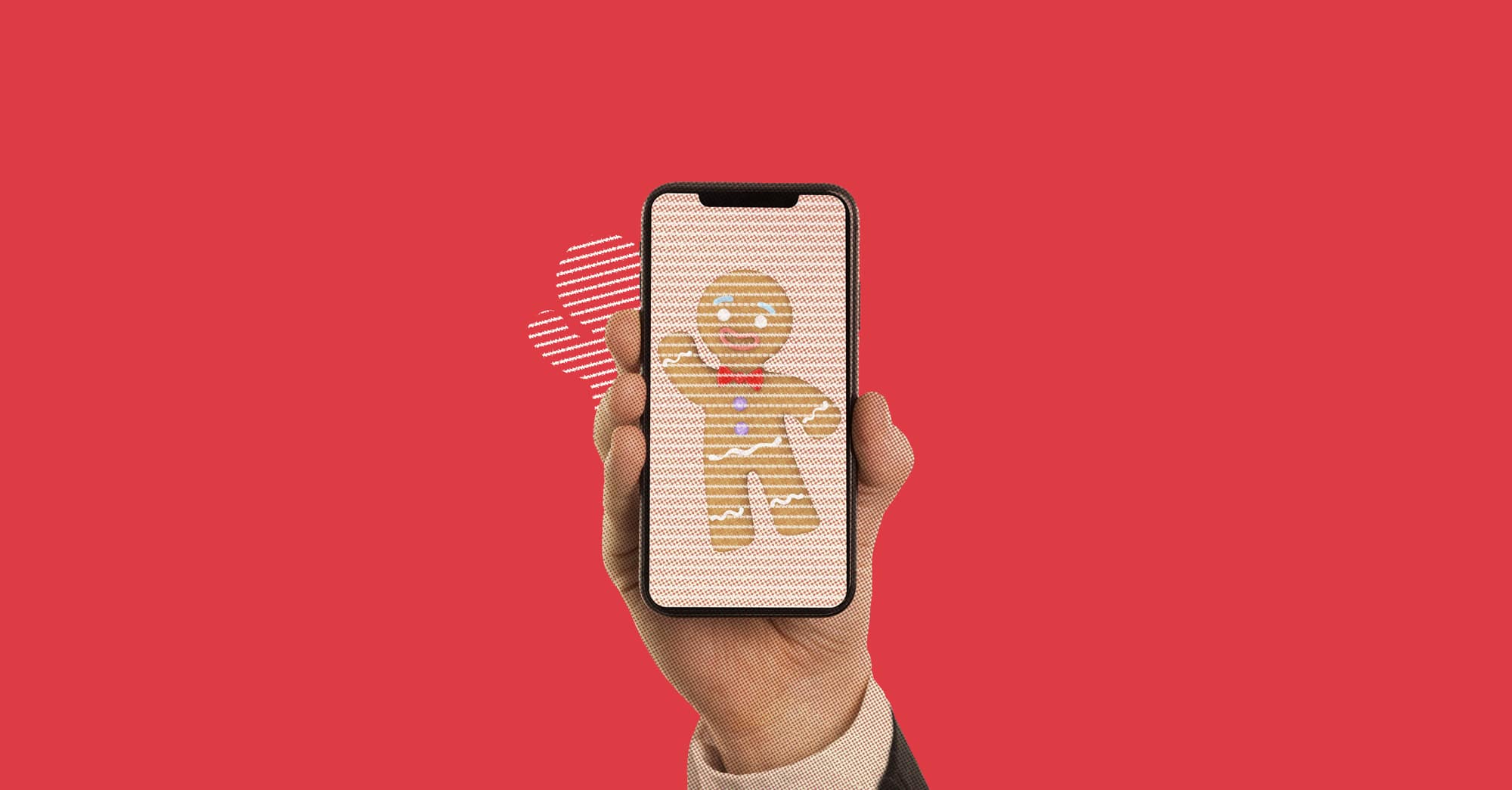 Mano sosteniendo un teléfono con imagen de galleta de jengibre sobre fondo rojo.