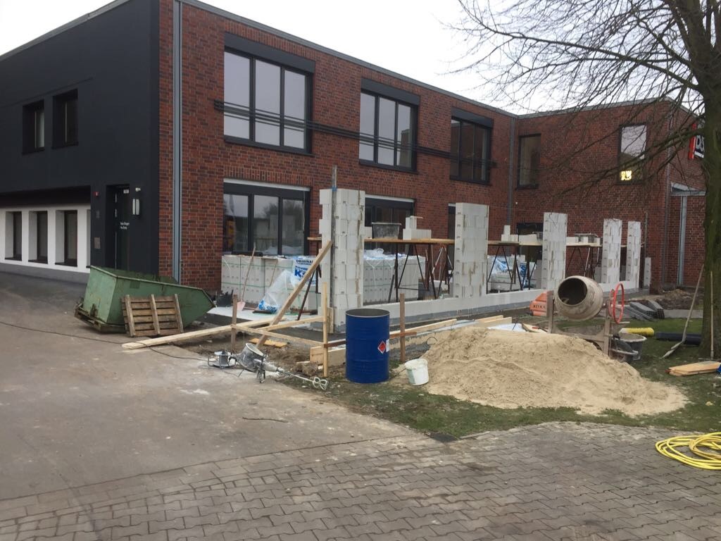 Baustelle: Rohbau eines Gebäudes mit Ziegelmauerwerk. Bauarbeiten, Betonmischer, Baumaterialien.