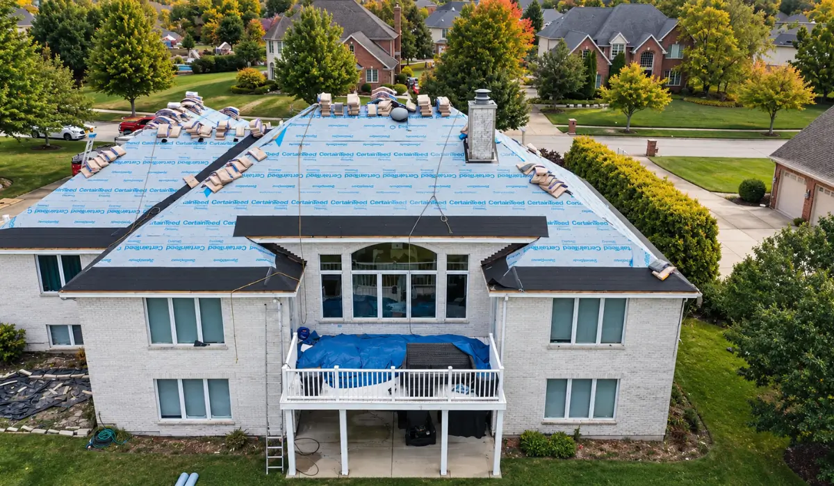 Illinois home undergoing roof installation with exposed underlayment and roofing materials during roof warranty-related work.