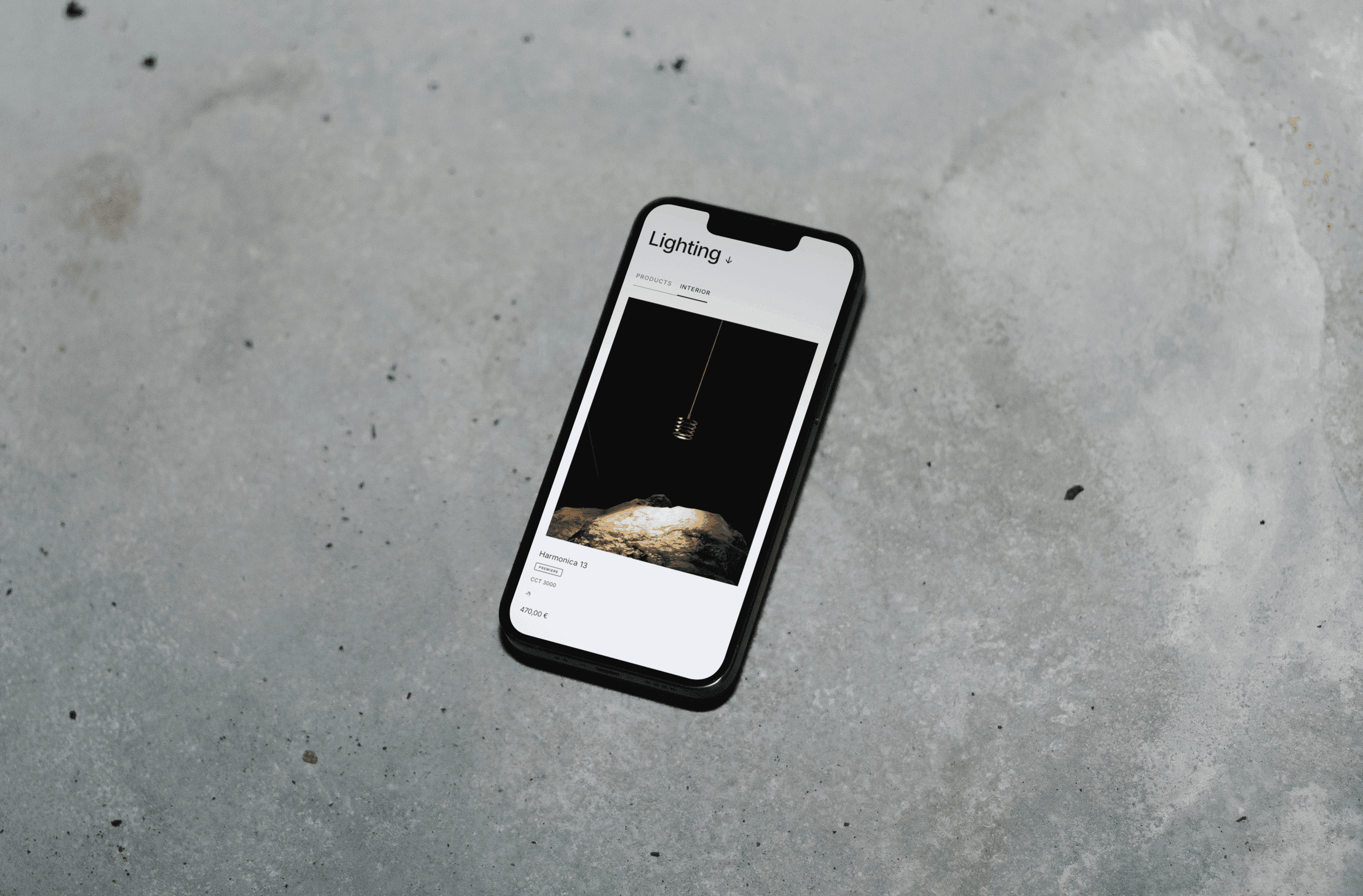 A smartphone lies on a gray surface, displaying a black screen with faint details visible.