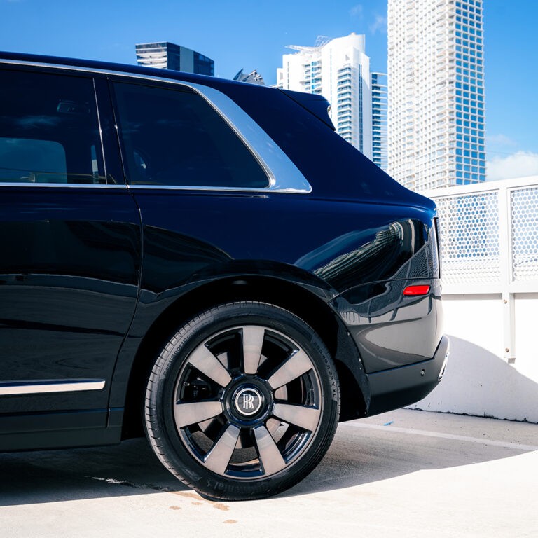 Close-up of the rear wheel and side profile of a black Rolls-Royce Cullinan.