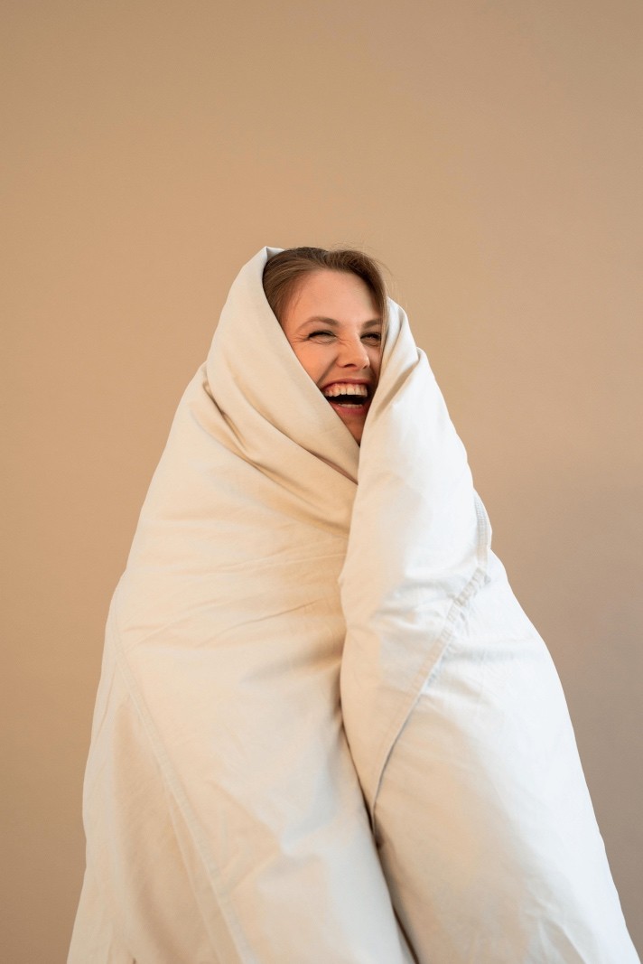 Sesja zdjęciowa dla Skin Concept – kobieta owinięta kołdrą