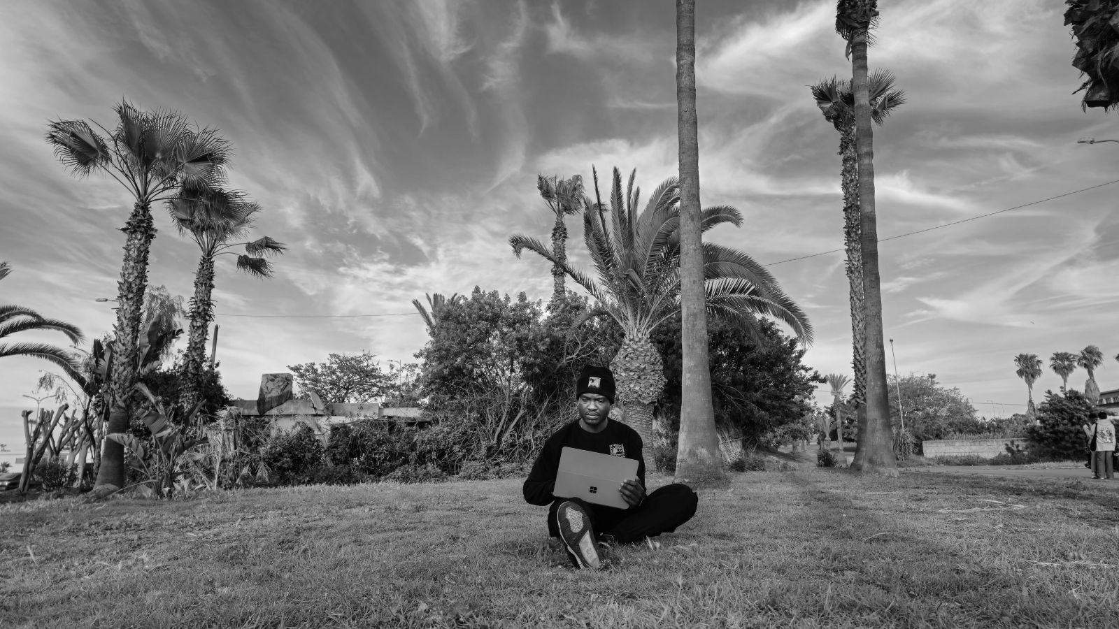 Samuel G. sumo sitting in a field with his laptop enjoying nature