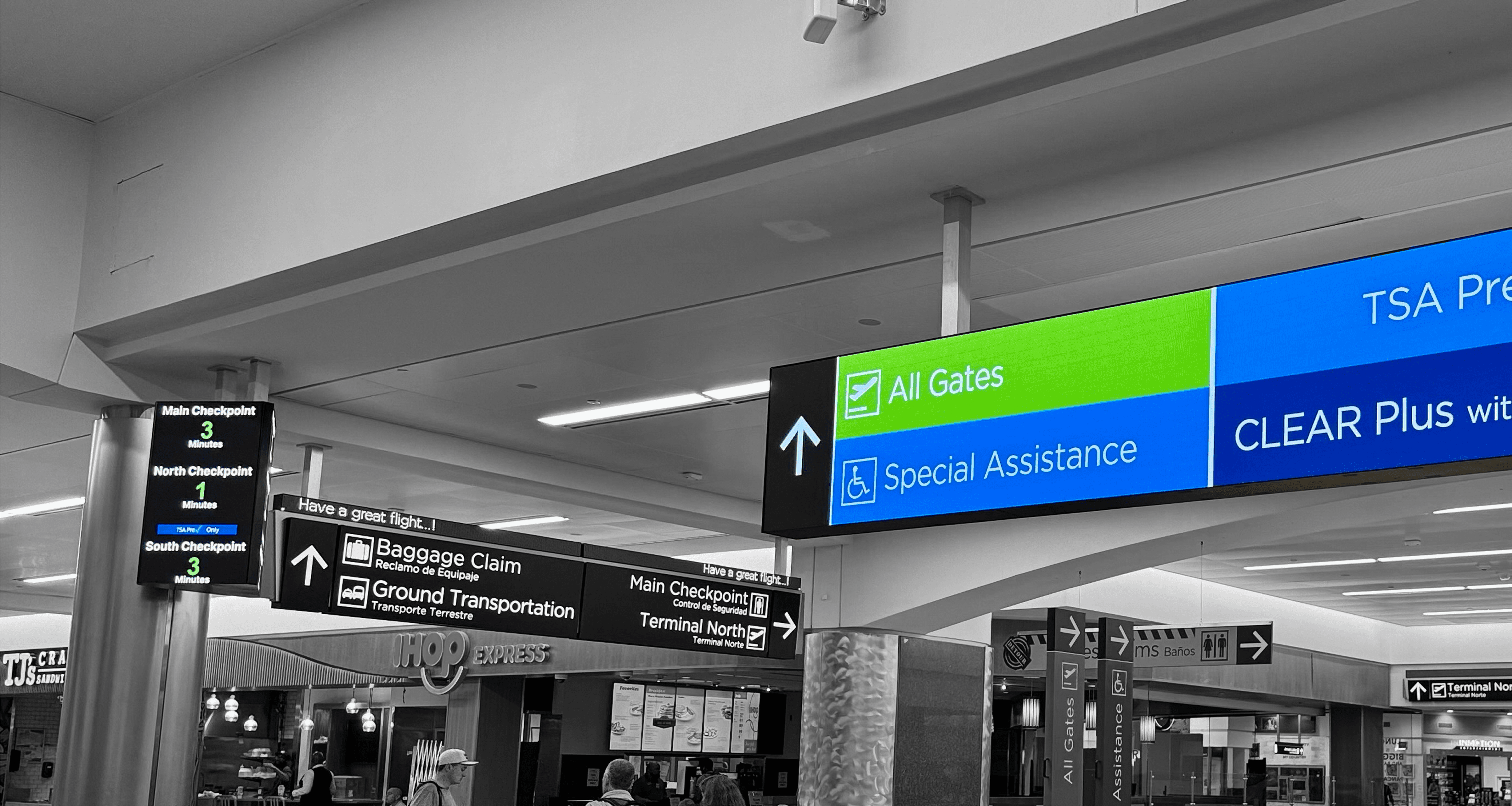 A photo of multiple signs hanging from the ceiling in an airport