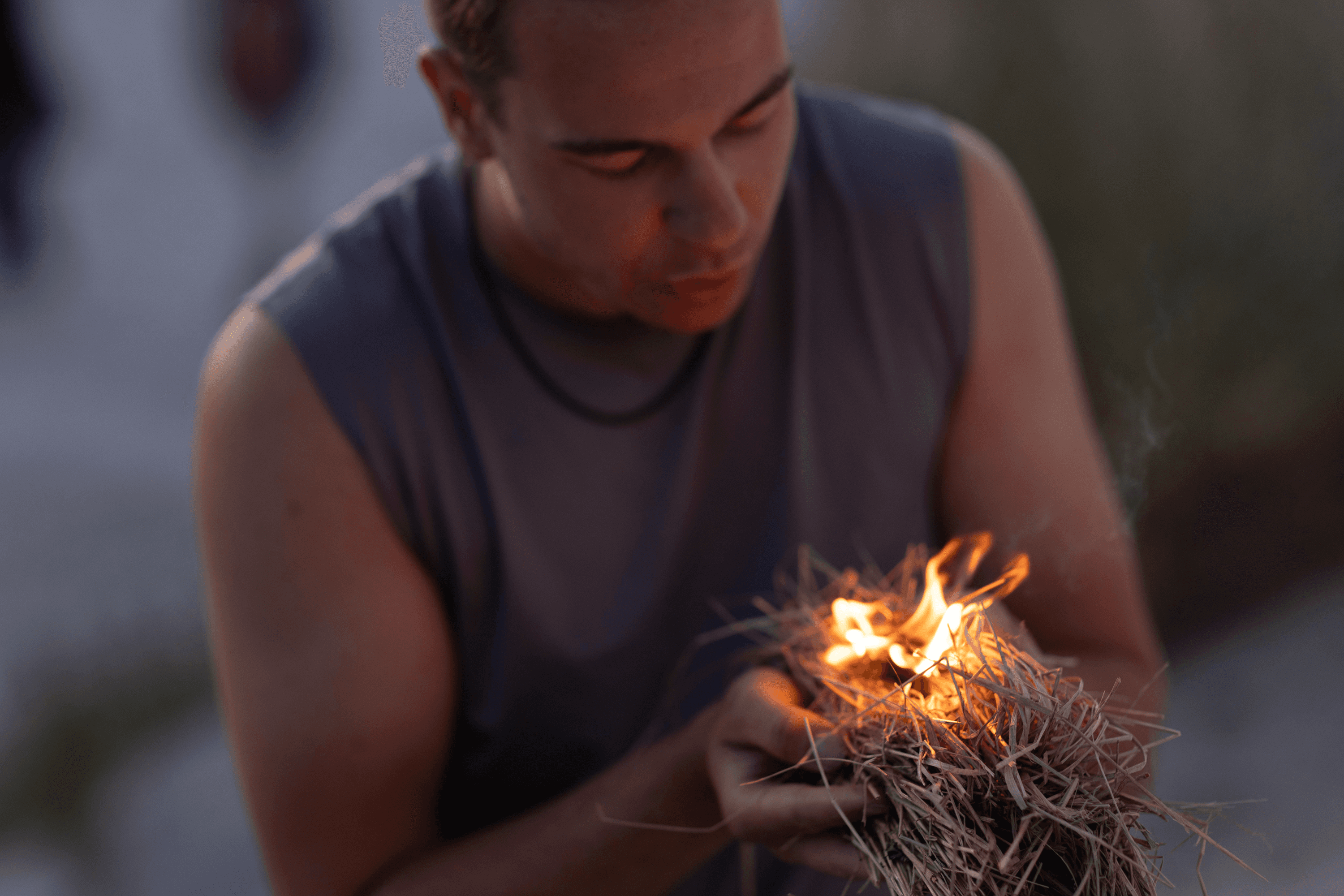 Man blowing sparks onto dry grass