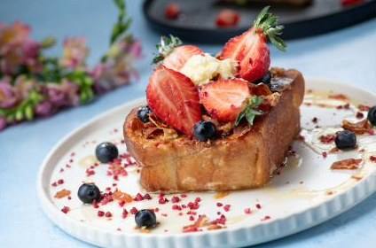 Brioche French toast topped with strawberries, blueberries and honey