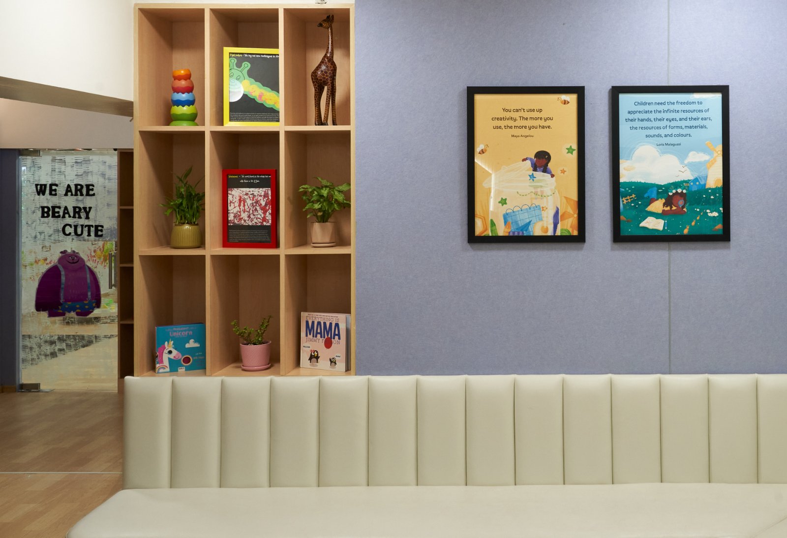 Nature-inspired preschool entrance with sculptural tree partitions and suspended green leaf ceiling panels.