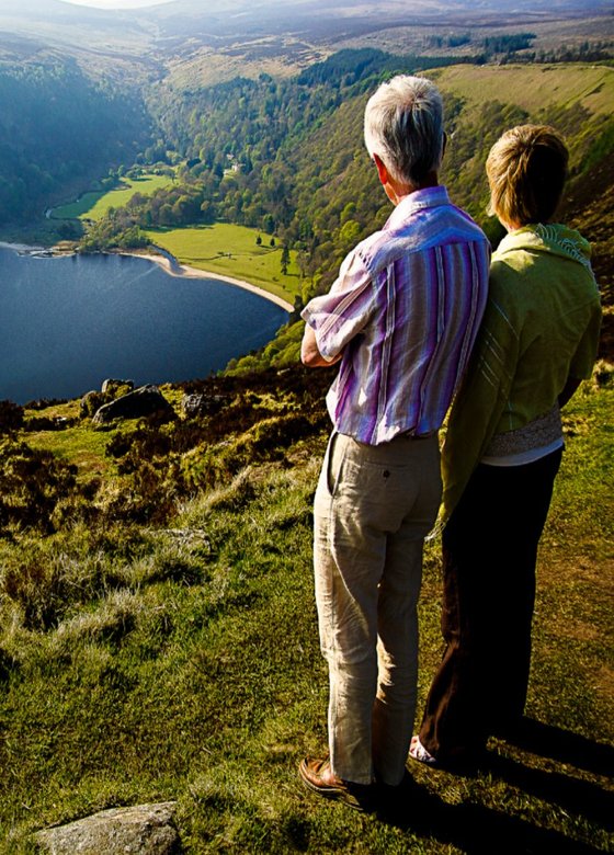 man standing near cliff looking at body of water during daytime